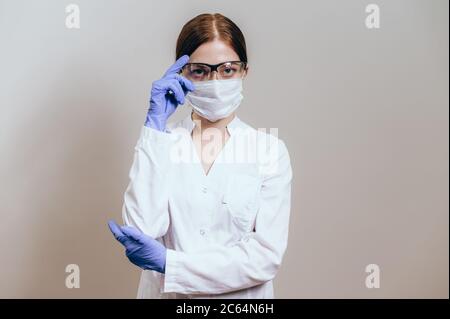 Ärztin oder Krankenschwester trägt eine Gesichtsmaske und Schutzbrille. Ärztin in einem weißen Mantel trägt eine Schutzmaske für die Arbeit Stockfoto