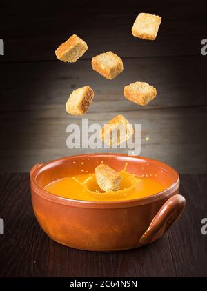 Croutons fallen in eine spritzende Kürbissuppe Stockfoto