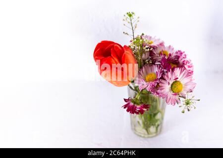 Tulpe und rosa Blumen in einer Glas-Tasse auf weißem Hintergrund. Stockfoto