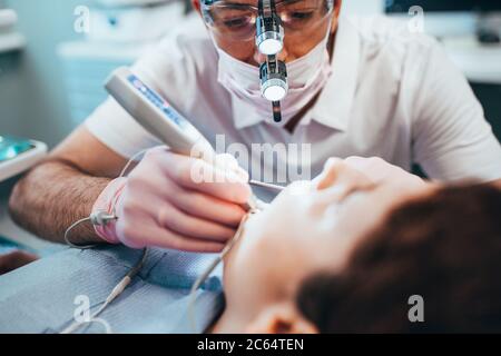 Ein Zahnarzt bei der Arbeit verwendet ein lokales LED-Licht - die Wirkung von ultravioletter Strahlung auf eine Zahnfüllung Stockfoto