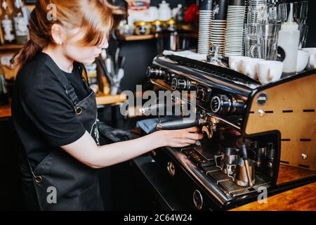 Barista Mädchen macht Espresso in einem Café - professionelle Kaffeemaschine Stockfoto