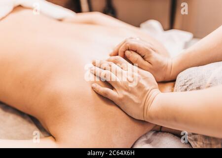 Zweihand-Massage mit dem harten Rücken - tiefe Wirkung auf die Muskulatur des Patienten Stockfoto