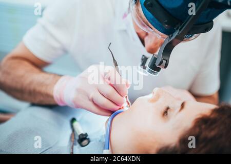 Zahnarzt während der Arbeit mit einem Patienten in einem Zahnstuhl - behandelt Pulpitis, reinigt den Zahnkanal und legt eine Füllung Stockfoto