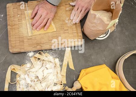 Nahaufnahme eines Paares, das in einer Küche steht und frische hausgemachte Tagliatelle-Pasta zubereitet. Stockfoto