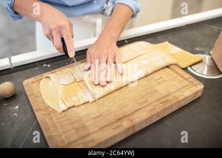 Frau, die in einer Küche steht und frische hausgemachte Tagliatelle-Pasta zubereitet. Stockfoto