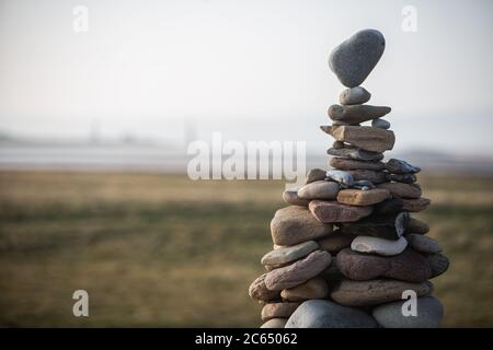 Ein Turm aus Steinen verschiedener Größen, gestapelt in einer Kaira, der obere Stein, der auf einem Punkt balanciert. Stockfoto