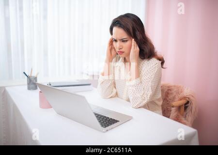 Junge Geschäftsfrau fühlt sich müde und hält den Kopf Stockfoto