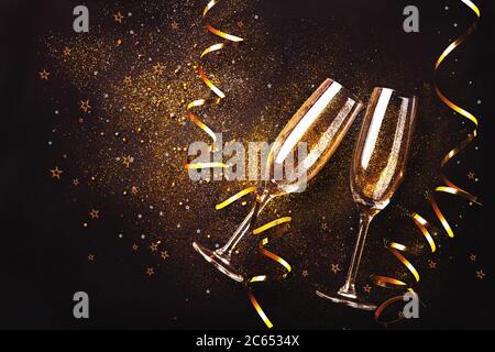 Feier Toast mit Champagner. Zwei Sektflöten mit goldenen Bächerchen auf dunklem Hintergrund Stockfoto