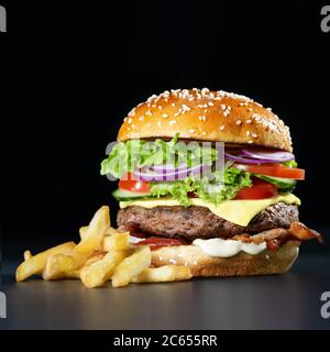 Frischer, leckerer Burger mit knusprigen pommes auf dunklem Hintergrund Stockfoto