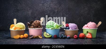 Verschiedene bunte Eis in Papierbecher auf dunklen rustikalen Hintergrund Stockfoto