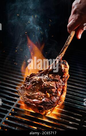 Rindersteak auf dem Grill mit Rauch und Flammen Stockfoto