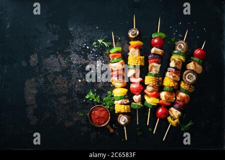 Hühnerkebabs auf Spieße mit Pilzen und Gemüse auf dunklem Hintergrund Stockfoto