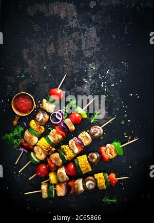 Hühnerkebabs auf Spieße mit Pilzen und Gemüse auf dunklem Hintergrund Stockfoto