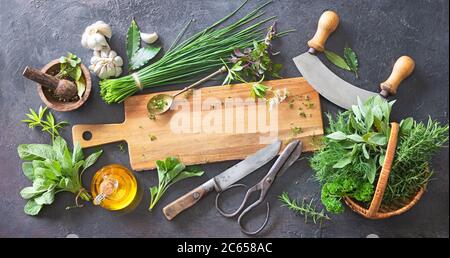 Verschiedene frische Kräuter aus dem Garten mit Küchenutensilien auf rustikalem Tisch. Draufsicht mit Kopierbereich Stockfoto