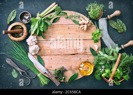 Verschiedene frische Kräuter aus dem Garten mit Küchenutensilien auf rustikalem Tisch. Draufsicht mit Kopierbereich Stockfoto