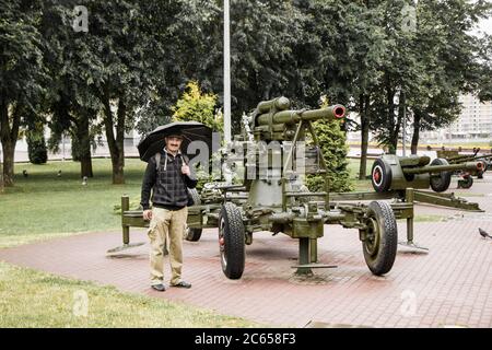 Witebsk, Weißrussland - 1. Juli 2018: Männliche touristische Ansicht die Ausstellung der sowjetischen Militärausrüstung des Zweiten Weltkrieges auf dem Siegesplatz am regnerischen Sommertag. Stockfoto