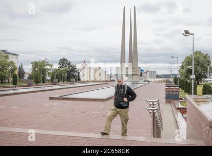 Witebsk, Weißrussland - 1. Juli 2018: Asiatischer Tourist mit Rucksack spaziert an einem bewölkten Tag entlang des Siegesplatzes. Stockfoto