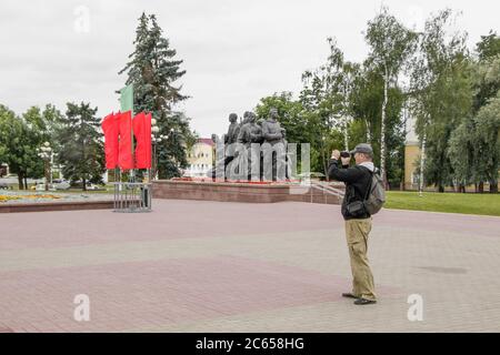 Witebsk, Weißrussland - 1. Juli 2018: Ein Tourist mit Rucksack macht an einem bewölkten Tag ein Amateurvideo auf dem Siegesplatz. Stockfoto