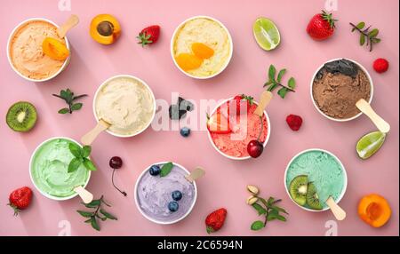 Verschiedene bunte Eiscreme-Sorten mit Früchten in Pappbechern auf rosa Hintergrund Stockfoto