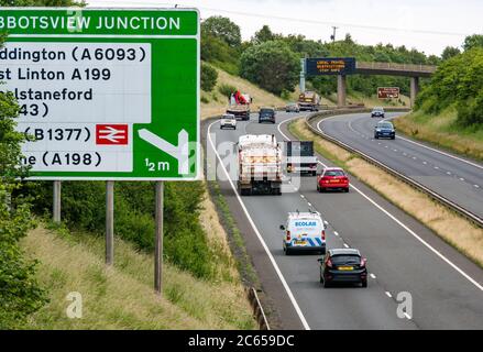 East Lothian, Schottland, Großbritannien, 7. Juli 2020. Covid-19 neue Meldung auf A1-Gantry: Die dritte Version der Pandemie-Meldung erscheint auf der über-Gantry in der Nähe von Haddington, die lautet "Lokale Reisebeschränkungen sicher bleiben", da Schottland in Phase 3, die nächste Woche erwartet wird, eingeht. Der Verkehr auf der zweispurigen Fahrbahn ist viel schwerer als in den letzten Monaten zu sehen war Stockfoto