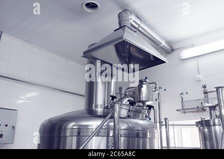 Belüftungssystem in einer Brauerei - Absaughaube über Bierbrautanks, getönt Stockfoto