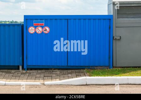 Eingezäunter blauer Müllcontainer mit Brandschildern. Hochwertige Fotos Stockfoto