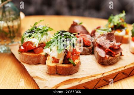 Bruschettas mit Rindfleisch, Tomaten und Käse auf Holzbrett, getönte Stockfoto