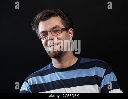 Foto von lächelndem bärtigen jungen Mann in einer Brille Stockfoto