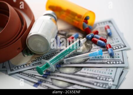 Geld und Pillen in Pillenflasche und Spritze auf dem Tisch Stockfoto