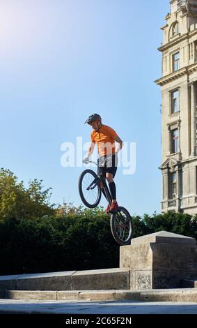 Trial Biker steht auf dem Hinterrad seines Mountainbikes an einem schönen sonnigen Tag über blauem Himmel, Konzept des aktiven Lebensstils Stockfoto