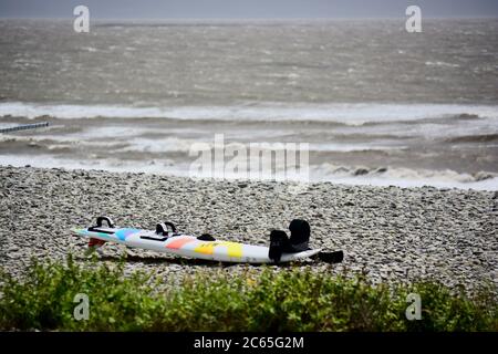 Wassersport in Barry an der Südwalesküste. Menschen genießen die Brandung an einem stürmischen Tag starten auf dem Kiesstrand in Cold Knap und reiten die Wellen. Stockfoto