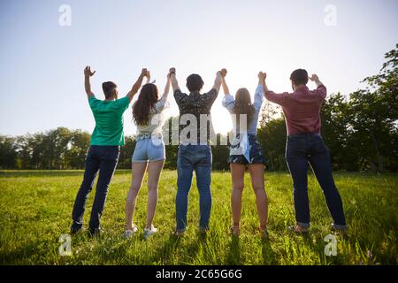 Die Hände der jungen Leute in einem Sommerpark angehoben Stockfoto