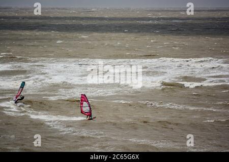 Wassersport in Barry an der Südwalesküste. Menschen genießen die Brandung an einem stürmischen Tag starten auf dem Kiesstrand in Cold Knap und reiten die Wellen. Stockfoto