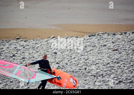 Wassersport in Barry an der Südwalesküste. Menschen genießen die Brandung an einem stürmischen Tag starten auf dem Kiesstrand in Cold Knap und reiten die Wellen. Stockfoto