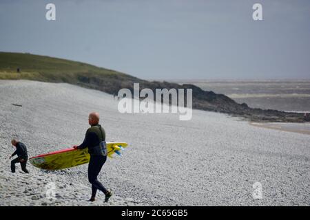 Wassersport in Barry an der Südwalesküste. Menschen genießen die Brandung an einem stürmischen Tag starten auf dem Kiesstrand in Cold Knap und reiten die Wellen. Stockfoto