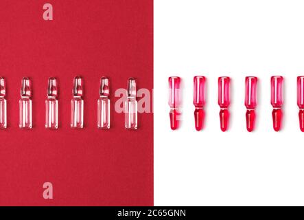 Ampullen für Injektionen mit roter und transparenter Flüssigkeit auf isoliertem weißem und dunkelrotem Hintergrund. Medizin, Gesundheitswesen und Pharmazie Konzept. Flach liegend. Stockfoto