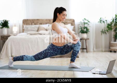 Schulung Zu Hause. Asiatische Mädchen Tun Stretching Übungen Vor Dem Laptop Stockfoto