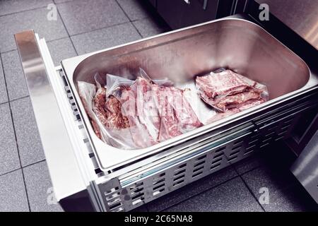 Lagerung von fertig-zu-kochen Steaks in der Restaurantküche, gekühlte Schublade, Vakuumbeutel, getönte Stockfoto