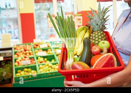 Frau hält einen Korb mit Obst und Gemüse im Supermarkt Stockfoto