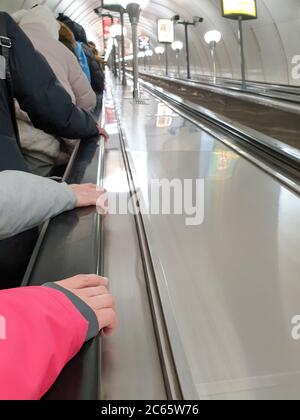 Die Leute fahren mit einer langen Rolltreppe in der U-Bahn. Stockfoto