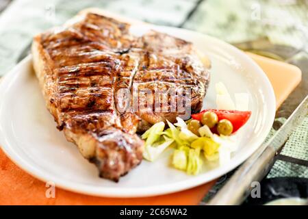 Gegrilltes oder gegrilltes Florentiner Steak auf einem Teller serviert mit frischem Salat garnieren in Nahaufnahme niedrigen Winkel mit flachen dof Stockfoto