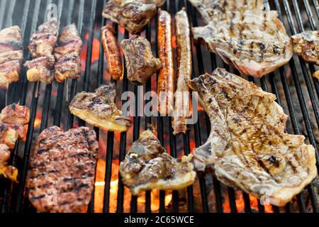 Auswahl an verschiedenen Fleisch Grillen auf einem BBQ-Feuer über die heißen Kohlen in Nahaufnahme Vollformat mit Rindfleisch, Würstchen und Spieße Stockfoto