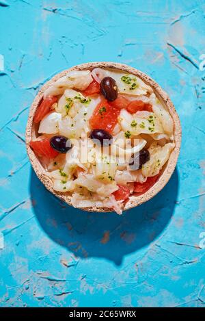 Blick in den hohen Winkel von einem Teller mit esqueixada de bacalla, ein kaltes Gericht mit Kabeljau, Tomaten, Zwiebeln und schwarzen Oliven, und mit Olivenöl, Typi gekleidet Stockfoto