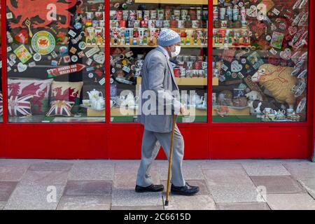 Cardiff, Wales, Großbritannien. Juli 2020. Ein älterer Mann mit Gesichtsmaske kommt an einem walisischen Souvenirladen im Stadtzentrum von Cardiff vorbei. Der walisische Gesundheitsminister Vaughan Gething sagt, dass die walisische Regierung weiterhin Beweise dafür ansieht, ob Gesichtsbedeckungen an öffentlichen Orten obligatorisch sein sollten. Kredit: Mark Hawkins/Alamy Live Nachrichten Stockfoto