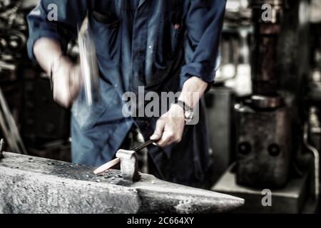 Schmied arbeitet ein glühendes Eisen in einer alten Schmiede Stockfoto