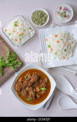 Huhn Masala oder Curry mit Ghee Reis oder biriyani, Biryani Reis in einem quadratischen Tischgares weiß in Farbe mit grünen Kokosnuss Minze Chutne und Gemüse gelegt Stockfoto