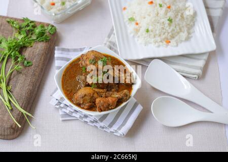 Chicken Masala Curry mit Ghee Reis oder Biryani Reis, in einem quadratischen Tischwäsche weiß in Farbe mit grünen Kokosnuss Minze Chutne und Raita platziert Stockfoto