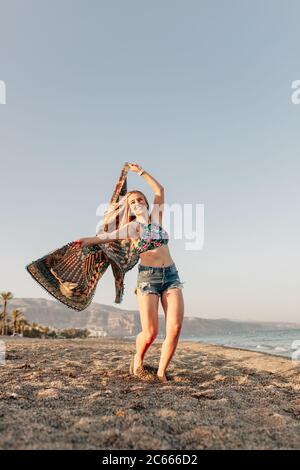 Frau läuft und hält Schal auf Welle entspannen und glücklich am Strand Stockfoto