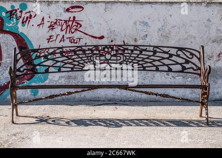 Alte Eisenbank auf einer bemalten Wand in Essaouira Stockfoto