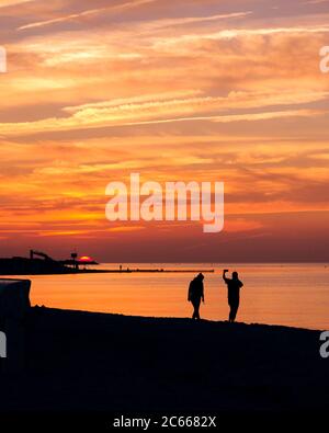 Paar am Strand bei Sonnenuntergang, fotografiert, Selfie, Silhouetten Stockfoto